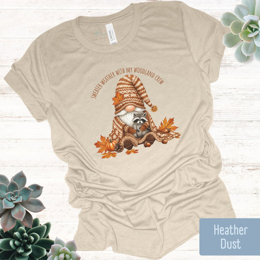 Beige t-shirt with a raccoon gnome graphic and text on a white background with succulents.